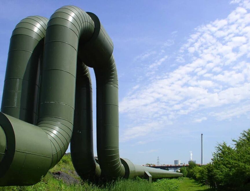 Image of two large green pipes curving up and down, with a blue sky in the background