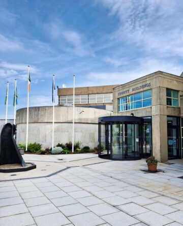 Image of the exterior of the Wicklow County Council bbuilding, with blue sky and flags