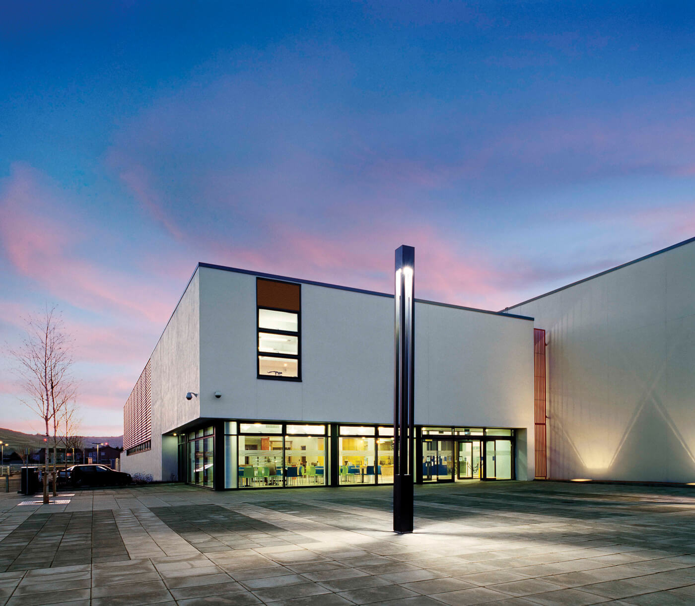 Image of a white building lit up with a blue and pink sky above