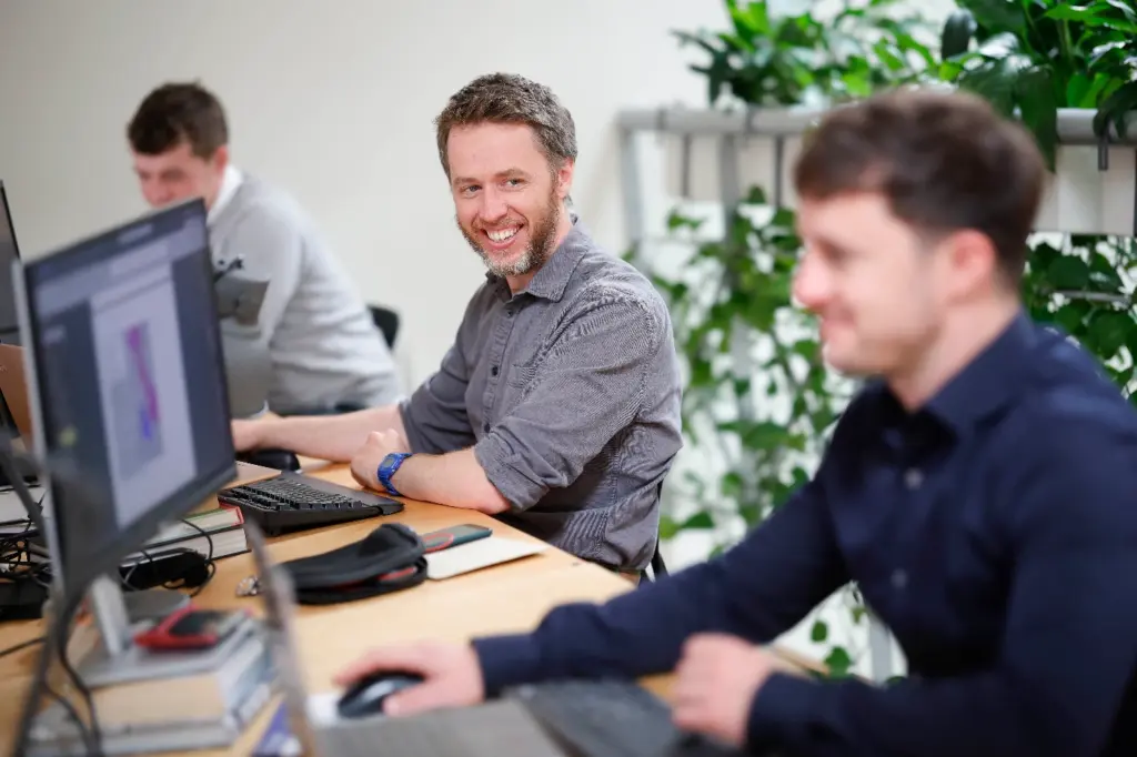 Codema staff members at their desks working. Two men are in focus, one is smiling at the other