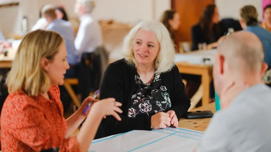 Two women and a man site at a table at a Codema workshop having a discussion