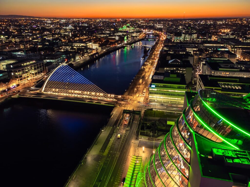 Drone shot of Dublin City with the Convention Centre lit up green and light reflecting on the River Liffey