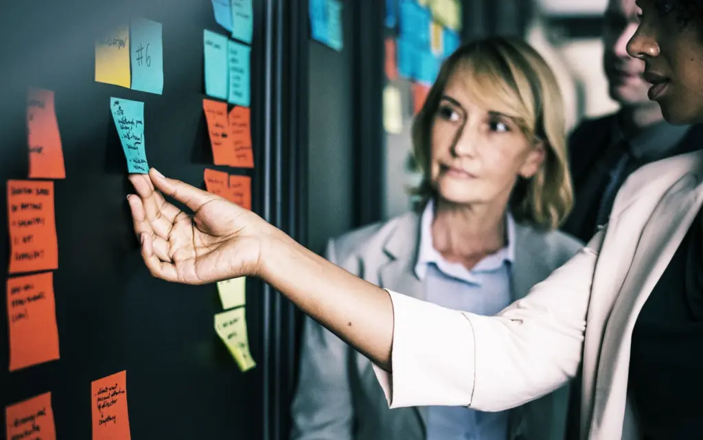 Stock photo of people putting post-it notes on a board