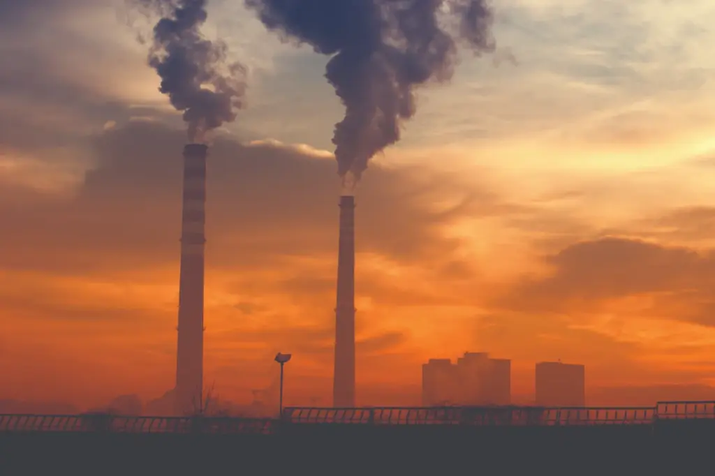 Image of two stacks with smoke coming out of them against an orange sky