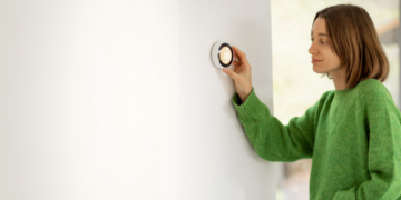 Woman adjusting a thermostat on the wall